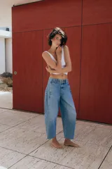 Jeans de tiro medio con pernera holgada tipo barrel que se estrecha hacia el tobillo, acabado con bajo sin costura, bolsillos delanteros y bolsillos de plastrón en la espalda. Cierre frontal con cremallera y botón.