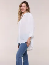 Camisa Magaschoni de silueta holgada y tejido texturizado color blanco, con cuello camisero, cierre frontal de botones, mangas largas con presilla para arremangar y diseño asimétrico con espalda más larga.