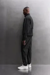 Chaqueta negra regular fit, confeccionada en tejido técnico con algodón. Presenta cuello subido, manga larga, forro interior de red y abertura en la espalda para transpiración. Incluye bolsillos con cierre de cremallera en la cadera, acabados elásticos y cierre frontal con cremallera.