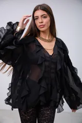 Blusa de tela semitransparente color negro, con diseño de volados verticales a lo largo del frente y en las mangas. Presenta cierre frontal con botones y cuello en V.