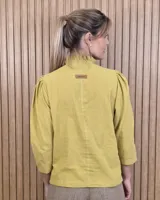 Camisa de algodón color blanco, con cuello alto con volados, mangas tres cuartos con detalles de bordado ingles y cierre frontal con botones de nácar.