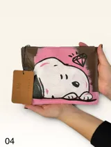 Sobre de cuero marrón con diseño pintado a mano que presenta al personaje Snoopy sobre un fondo rosado y la palabra 'heal'. Cuenta con cierre superior y etiqueta de cuero colgante.