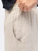 Pantalón de lino de corte holgado y tiro ajustable, con cintura elástica y cordón. Presenta bolsillos laterales y un bolsillo trasero.