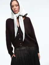 Cardigan de punto color marrón oscuro, con escote en V, manga larga y cierre frontal con botones metálicos dorados.