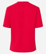 Blusa blanca de poliéster con cuello redondo, mangas cortas, cierre trasero en forma de gota, pequeñas aberturas laterales y acabados en pespuntes en las mangas y el cuello.