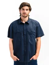 Camisa negra de manga corta con cuello clásico, cierre frontal con botones y dos bolsillos de parche en el pecho. Corte recto y estilo utilitario.