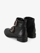 Bota corta marrón de cuero con dos correas con hebillas metálicas en la parte delantera y cierre lateral.