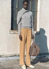 Pantalón de vestir color tostado con diseño de corte recto y tiro medio. Presenta detalle de pinzas frontales, trabillas para cinturón y cierre oculto con cremallera, botón y ganchos.