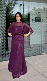 Vestido largo de fiesta color gris, confeccionado en tejido con textura calada tipo red. Presenta un diseño de silueta fluida con mangas amplias tipo murciélago y escote redondo.