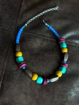 Collar corto con cuentas de madera, acrílico y cristales en tonos turquesa, amarillo, marrón y fucsia.