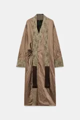 Kimono de la colección ZW de Zara, confeccionado en tejido marrón con acabado satinado. Presenta solapas anchas en tono verde con estampado estilo jacquard y flecos largos colgantes en el frente. Cuenta con mangas largas con puños estampados y bolsillos laterales ocultos.