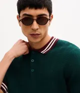 Polo de manga corta confeccionado en tejido de punto texturizado. Presenta cuello, puños y ruedo con diseño a rayas en contraste. Cuenta con una abertura frontal con botones.
