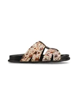 Sandalias planas con tiras cruzadas de pelo con estampado animal print tipo vaca en tonos blancos y marrones, con suela negra.