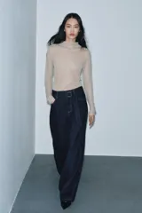 Jeans de tiro alto con pierna ancha, confeccionados en denim azul oscuro. Presentan cinco bolsillos, trabillas en la cintura y un cinturón ajustable del mismo tejido con hebilla metálica. Incluyen pespuntes marcados a tono y cierre frontal con cremallera y botón.