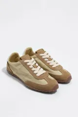 Zapatilla deportiva confeccionada en serraje, con detalle trasero en piel y suela de caucho con cuña interna.