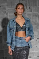 Campera de jean celeste con apliques de strass y cadenas en hombros y bolsillos.