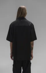 Camisa de manga corta con calce oversize, confeccionada en tejido de lyocell, con cuello clásico y cierre frontal de botones.