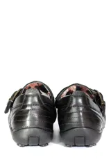 Zapato bajo de cuero negro con hebilla dorada.