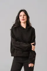 Buzo tipo canguro color negro, con capucha, mangas largas y corte holgado. Presenta un diseño minimalista sin estampados.