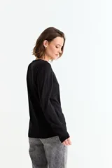 Sweater de punto liso color marrón topo, con cuello redondo y manga larga. Presenta un detalle de tres botones pequeños en la abertura del puño.