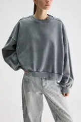 Buzo oversize gris de algodón con efecto acid wash, cuello redondo, hombros caídos, mangas largas y terminaciones acanaladas.