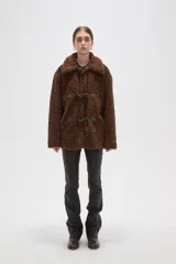 Campera de textura tipo corderito en color marrón, con cuello solapa y cierre frontal mediante tres botones tipo duffle con presillas de cuero sintético.