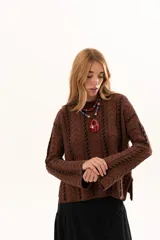 Buzo de tejido de punto color chocolate con diseño de trenzas verticales y detalles de costuras en contraste color negro. Presenta cuello redondo, mangas largas con terminación acampanada y aberturas laterales en el ruedo.