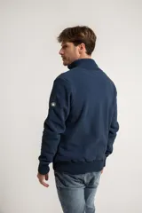 Campera de polar con cierre frontal, cuello alto tejido y puños y ruedo acanalados. Cuenta con un pequeño parche circular en la manga.