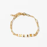 Pulsera dorada con eslabones tipo clip y tres cuentas rectangulares de color blanco con detalles dorados.