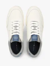 Zapatillas de baloncesto Tommy Hilfiger de corte bajo, color blanco con detalles en gris, azul y suela bitonal. Presentan exterior de piel con paneles de ante y mezcla de texturas, cordones blancos y detalles distintivos de la marca.