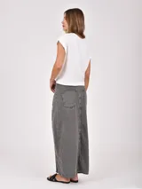 Falda larga de denim color gris oscuro, con diseño cruzado frontal (wrap) que se ajusta con botones plateados, creando una abertura pronunciada.