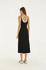 Vestido midi bicolor negro con detalles en blanco en el escote, sisas, aberturas laterales y ruedo. Diseño sin mangas con escote redondo y aberturas cut-out a los lados.