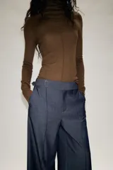 Pantalón culotte de tiro medio con pernera ancha y corta. Presenta nervios marcados en la parte delantera, bolsillos laterales y cierre frontal con cremallera, botón interior y hebilla ajustable en la cintura.