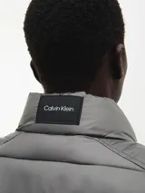 Chaleco gris con cierre frontal, cuello alto y bolsillos laterales con cierre.