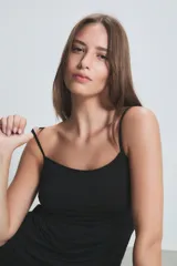 Musculosa de breteles finos en color beige, confeccionada en tejido suave y elástico, con diseño básico y ajuste al cuerpo.