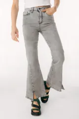 Jean azul claro de corte flare con aberturas en los tobillos y detalles rotos en las rodillas y muslos.