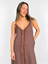 Vestido maxi de lino color blanco, con escote en V, tirantes finos regulables y detalles de flecos en el frente.