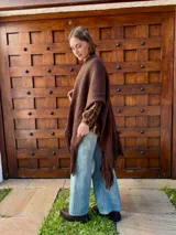 Ruana tejida en color chocolate, confeccionada en lana, con diseño de textura lisa y terminaciones con flecos largos en los extremos.