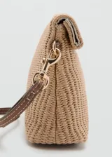 Cartera de mano de tejido trenzado color beige, con solapa y cierre de botón a presión metálico dorado. Incluye una correa de muñeca en tono marrón y herrajes dorados.