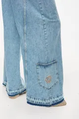 Jean de denim celeste de tiro alto y silueta wide leg, con costuras marcadas, bolsillos funcionales, bolsillo trasero inferior con bordado y terminación desflecada en el ruedo.
