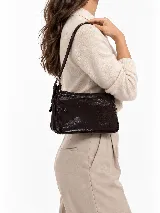 Cartera de cuero vacuno en color marrón, de diseño compacto, líneas simples y formato estructurado. Cuenta con correa corta ajustable para llevar al hombro y cierre superior.