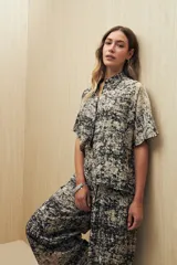 Conjunto de camisa y pantalón a rayas verticales en blanco y negro. La camisa es de manga corta, confeccionada en viscosa suave y fluida, con cuello clásico y botones al frente. El pantalón es de corte palazzo, con cintura alta y pernera ancha.