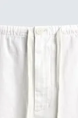 Pantalón de corte regular fit confeccionado en mezcla de algodón y lino. Presenta cintura elástica con cordón ajustable, cierre frontal con cremallera y botón, bolsillos laterales y bolsillo trasero de vivo con botón.