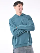 Hoodie de color verde azulado, con capucha y bolsillo canguro frontal. Presenta un corte holgado y puños y cintura acanalados.