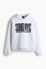 Canguro de felpa gris melange, con capucha de doble capa, bolsillo tipo canguro y estampado frontal con la leyenda 'SOHO NYC ATHLETICS DEPT' en color negro. Presenta hombros caídos y puños y bajo de punto acanalado.