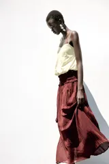 Top corto color crema confeccionado con lino, escote pico y tirantes finos. Detalle de espalda abierta con tira elástica horizontal y bajo abullonado con elástico interior.