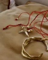 Collar tipo gargantilla con dije de flor metálica de acabado brillante, suspendido de un cordón doble de seda natural teñido a mano en color rojo.