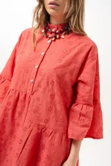 Vestido corto coral de broderie, con cuello camisero, cierre frontal de botones, mangas tres cuartos con volados y diseño escalonado en la falda.