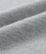 Cardigan gris de punto con cuello redondo, manga larga ajustada y bajo ajustado. Cierre frontal con botones.