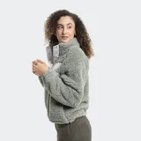Campera de polar tipo sherpa color verde, con cuello alto y cierre frontal parcial con botones a presión. Presenta un bolsillo frontal con cierre y detalle de marca Reef.